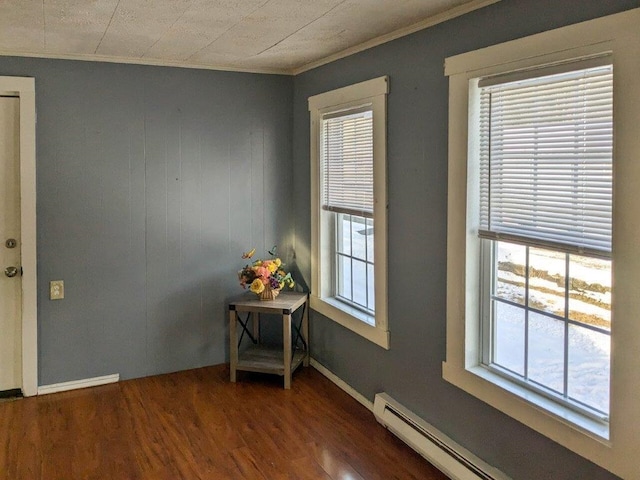 interior space featuring baseboard heating, dark hardwood / wood-style floors, and crown molding