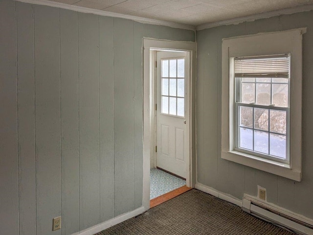 doorway with a baseboard radiator, ornamental molding, wood walls, and a wealth of natural light