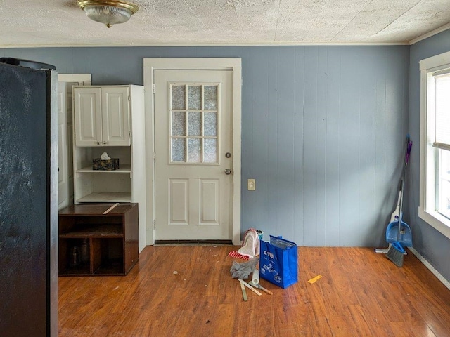 doorway to outside featuring crown molding, hardwood / wood-style flooring, and a wealth of natural light