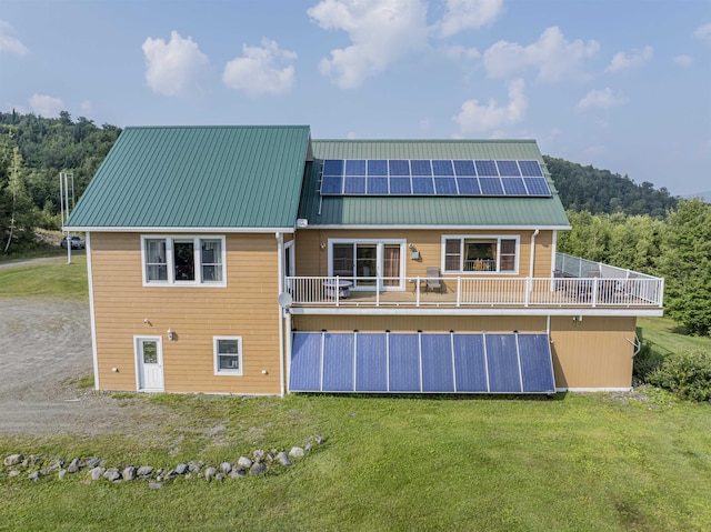 rear view of property featuring a yard and solar panels