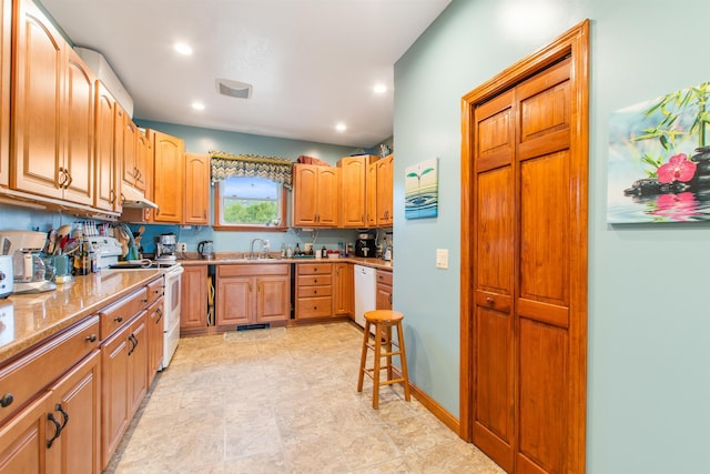 kitchen with white appliances, light stone countertops, and sink