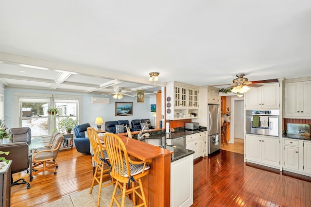 44 Winnicoash St, Laconia, NH 03246 - kitchen featuring stainless steel appliances, a wall mounted AC, light wood-type flooring, and kitchen peninsula