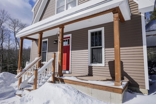 snow covered property entrance with covered porch