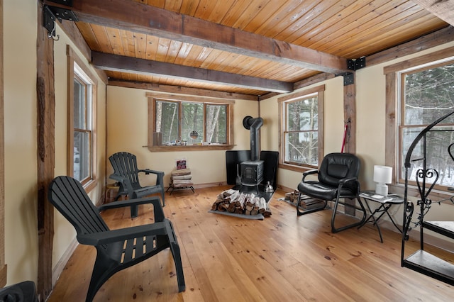 living area with a wood stove, wooden ceiling, beam ceiling, and light hardwood / wood-style flooring