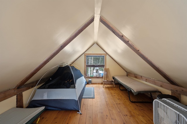 bedroom featuring vaulted ceiling with beams and light hardwood / wood-style floors