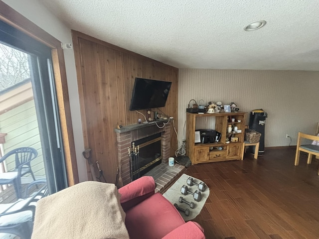 living room featuring dark hardwood / wood-style floors, a brick fireplace, and a textured ceiling