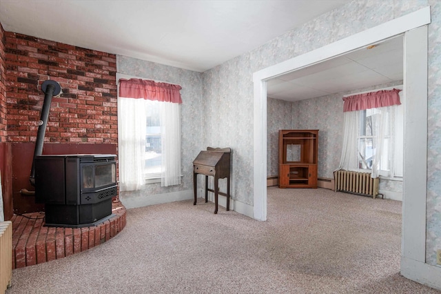 living room with a wood stove, radiator heating unit, and carpet flooring