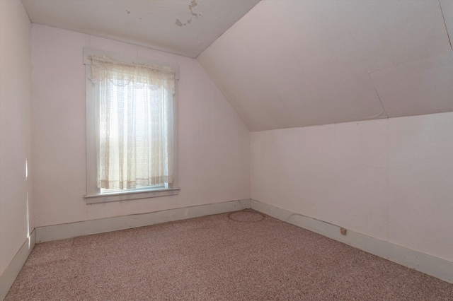 additional living space featuring vaulted ceiling and light colored carpet