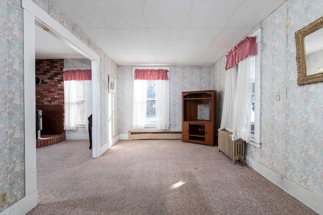 carpeted empty room featuring a baseboard heating unit and radiator heating unit