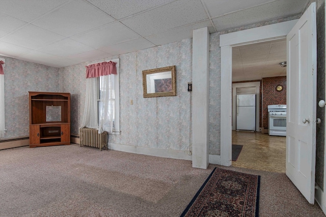 unfurnished living room featuring carpet flooring, radiator, and a drop ceiling