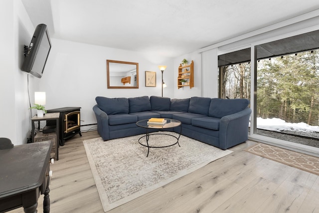 living room featuring a baseboard radiator, a wood stove, and light hardwood / wood-style floors