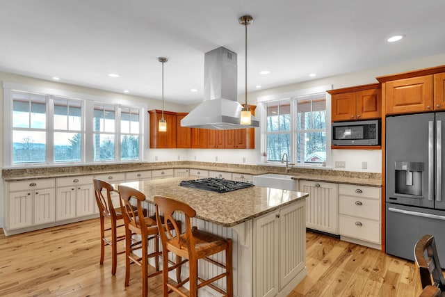 kitchen featuring a breakfast bar, appliances with stainless steel finishes, a center island, island exhaust hood, and decorative light fixtures