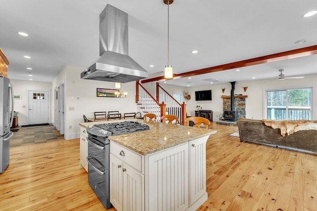 kitchen with island range hood, decorative light fixtures, light wood-type flooring, stainless steel appliances, and white cabinets