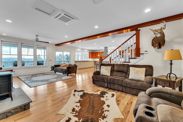 living room with ceiling fan, beam ceiling, and light hardwood / wood-style flooring