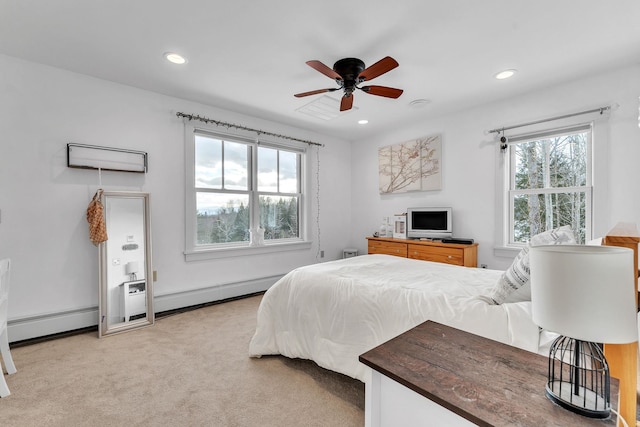 bedroom with multiple windows, light colored carpet, and baseboard heating