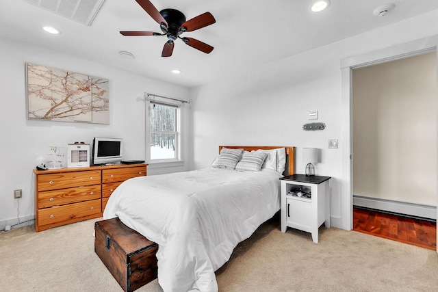 carpeted bedroom with ceiling fan and a baseboard heating unit