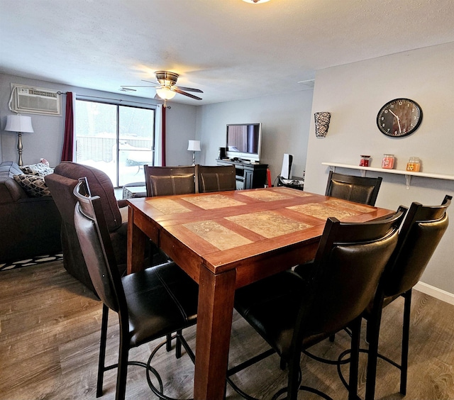 dining room featuring dark wood-type flooring, ceiling fan, and a wall unit AC