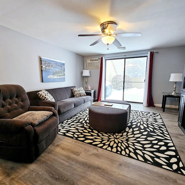 living room with hardwood / wood-style floors, a wall mounted AC, and ceiling fan