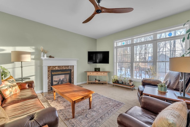 carpeted living room with a high end fireplace and ceiling fan