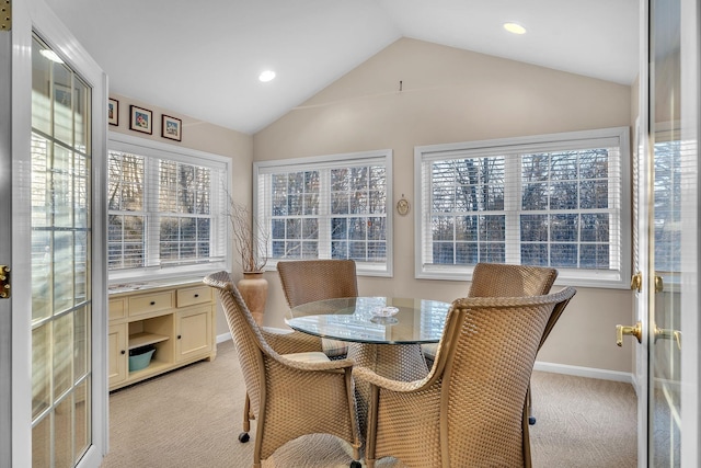 carpeted dining room with lofted ceiling