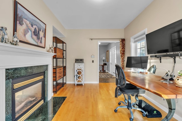 office featuring a high end fireplace and light hardwood / wood-style flooring