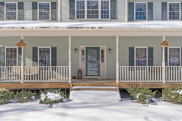 snow covered property entrance featuring a porch