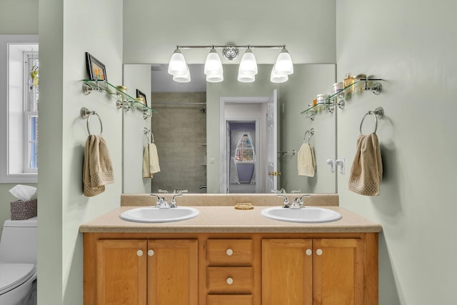 bathroom with vanity, toilet, and tiled shower