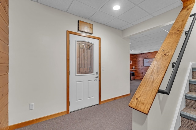 entryway featuring carpet, a paneled ceiling, and wooden walls