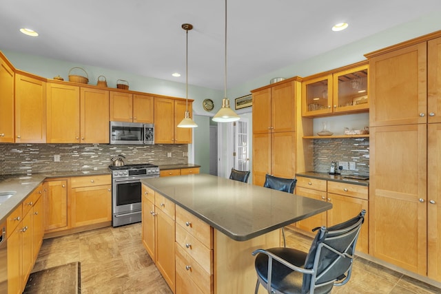 kitchen with pendant lighting, appliances with stainless steel finishes, a kitchen breakfast bar, a center island, and decorative backsplash