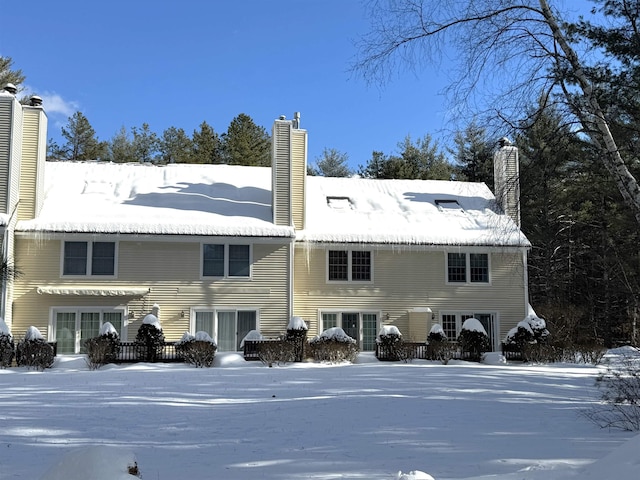 snow covered back of property featuring a chimney