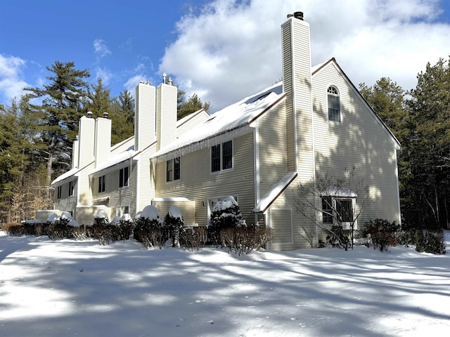 snow covered rear of property featuring a chimney