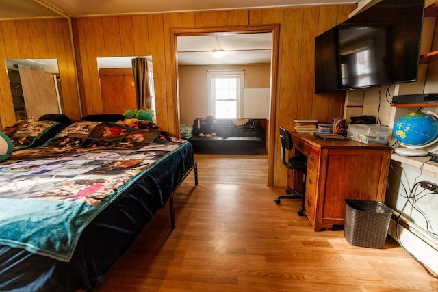 bedroom with wood walls and light hardwood / wood-style flooring