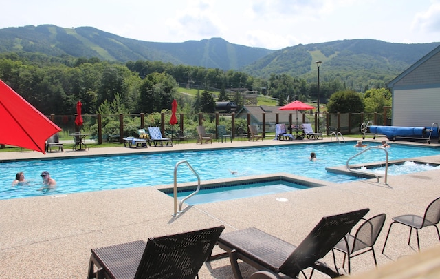 view of pool with a patio, a mountain view, and a community hot tub