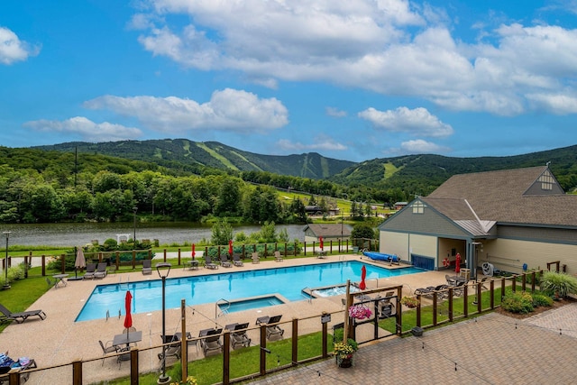 view of swimming pool featuring a water and mountain view and a patio