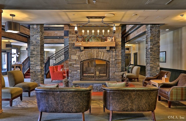 living room with a stone fireplace, wood-type flooring, and ornate columns