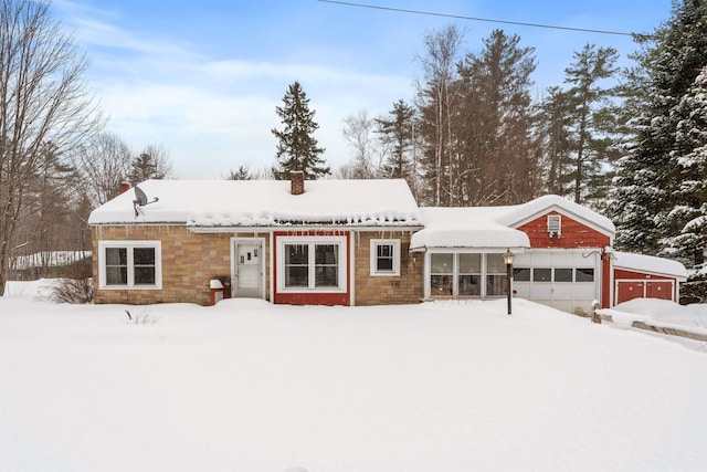 snow covered rear of property featuring a garage