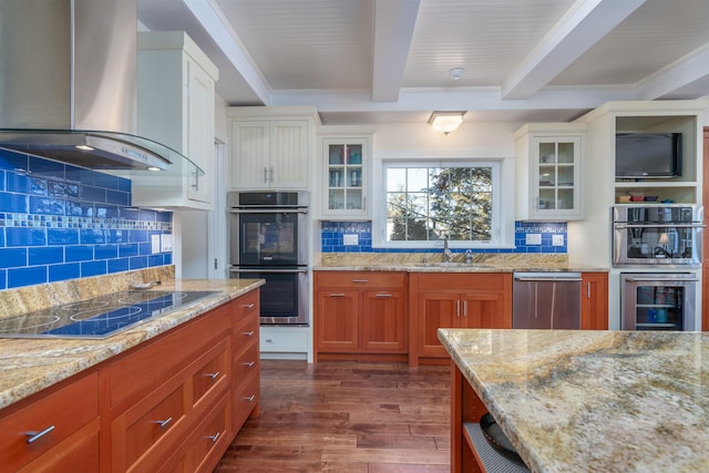 kitchen with wall chimney range hood, sink, beam ceiling, stainless steel appliances, and white cabinets