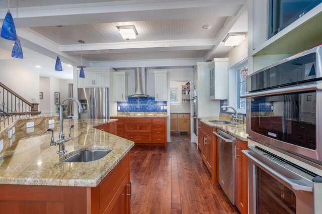 kitchen with a large island with sink, white cabinetry, wall chimney range hood, and stainless steel appliances