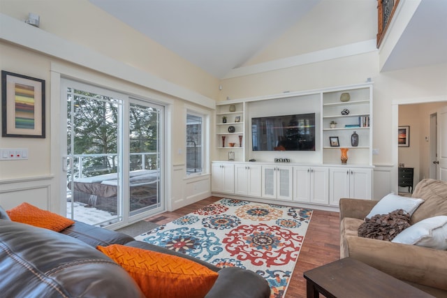 living room with built in shelves, dark hardwood / wood-style flooring, and high vaulted ceiling