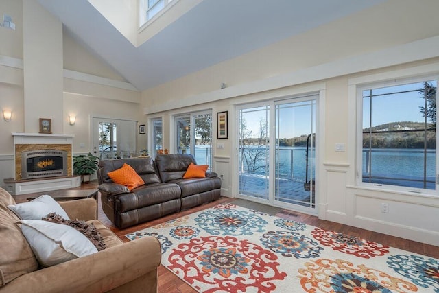 living room with a skylight, high vaulted ceiling, wood-type flooring, and a water view