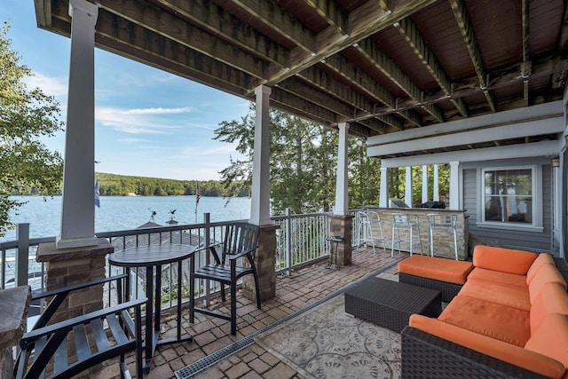 view of patio / terrace featuring an outdoor living space, a water view, and exterior bar