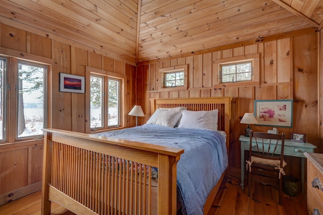 bedroom with hardwood / wood-style flooring, vaulted ceiling, and wooden walls