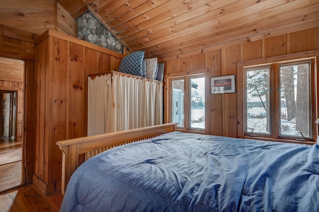 bedroom with multiple windows, vaulted ceiling, access to outside, and wooden walls