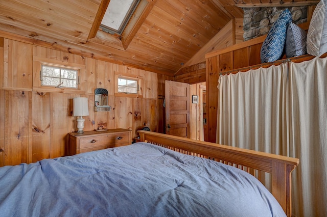 bedroom with vaulted ceiling with skylight, wood ceiling, and wood walls