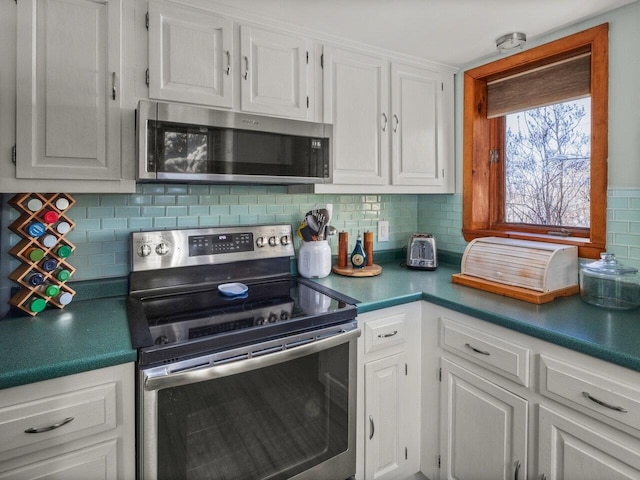 kitchen with tasteful backsplash, white cabinets, and appliances with stainless steel finishes