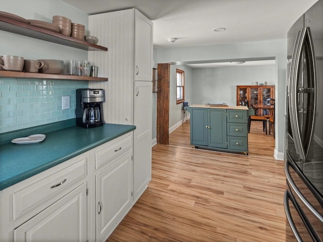 kitchen featuring white cabinetry, decorative backsplash, stainless steel fridge, and light hardwood / wood-style flooring