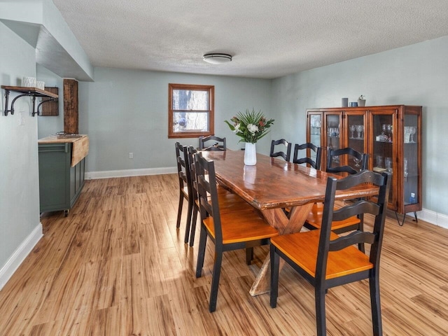 dining area with light hardwood / wood-style flooring and a textured ceiling