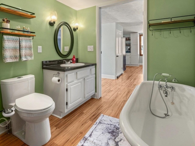 bathroom featuring vanity, a bathtub, hardwood / wood-style flooring, and toilet