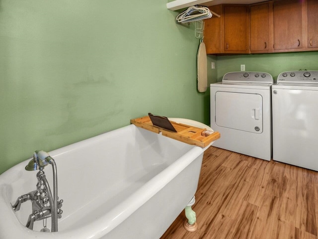 clothes washing area featuring cabinets, light wood-type flooring, and washer and clothes dryer