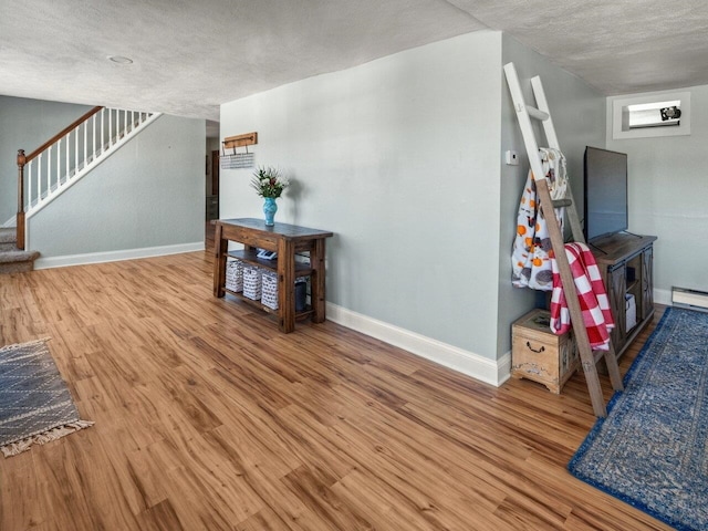 interior space with light hardwood / wood-style floors, a textured ceiling, and baseboard heating